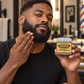 Castor oil pomade jar held by a man, clear lid and gold label for hair and beard