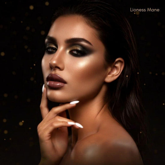 A close-up portrait of a woman with dramatic dark eye makeup, glossy mauve lipstick, and white manicured nails against a black background with subtle gold bokeh. The text 'Lioness Mane' appears in the top right corner.